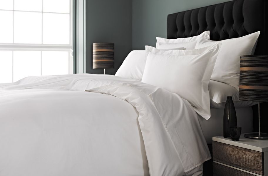 All white bedding with black headboard