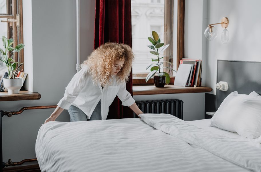 Woman making satin stripe white bedding bed