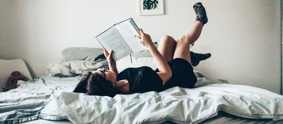 Woman relaxing on bed and reading a book