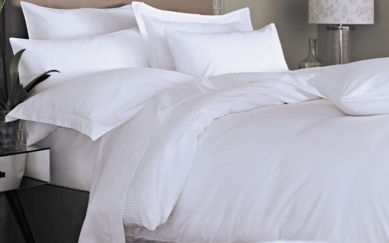 The VV300 5mm satin stripe 100% cotton duvet cover on a bed in a bedroom